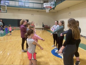 Participants learning how to play volleyball with members of the NC women's volleyball team. 