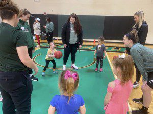 Young participants learn the basics of basketball from members of the NC women's basketball team. 